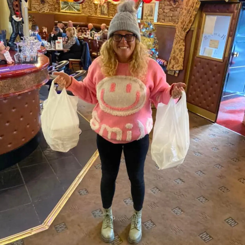 A customer in a pink sweater, smiling in a restaurant